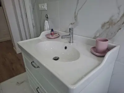 a bathroom sink with a pink cup and a pink candle at Sunflower House in Rome