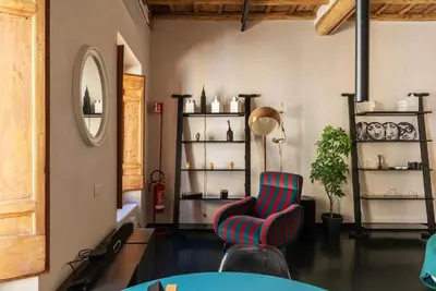 a living room with a chair and shelves of vases at GuestHost - Vintage-Modern Apartment Trastevere in Rome