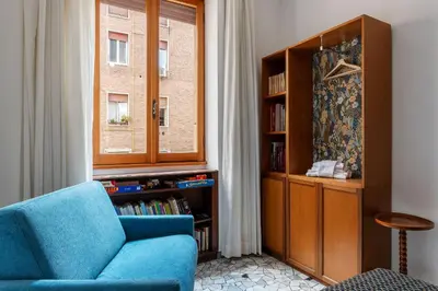 a living room with a blue chair and a book shelf at Casa Luisa - WelcomeToRhome in Rome