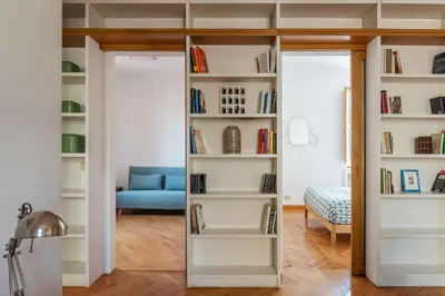 a room with a book shelf with a blue couch at Terrazza di Flamy - WelcomeToRhome in Rome