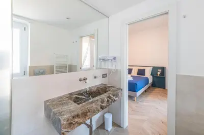 a bathroom with a stone sink and a bed at Victoria Rooms in Rome