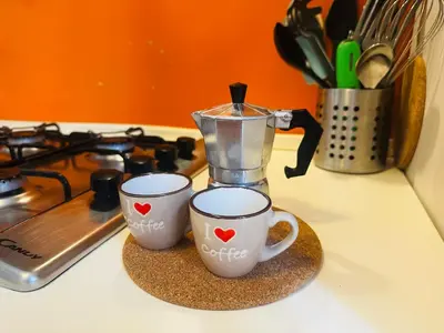 two coffee cups sitting on a counter next to a juicer at Little Colosseum Gem in Rome