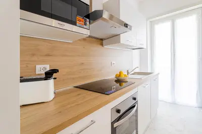 a kitchen with white cabinets and a wooden counter top at Vacanze romane - Domus chic Trastevere - Marconi by Hôtea in Rome