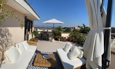a patio with two white couches and an umbrella at Chic Penthouse Retreat in Rome