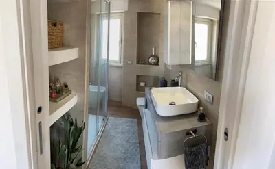 a bathroom with a sink and a glass shower at Chic Penthouse Retreat in Rome