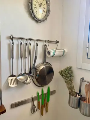 a bunch of utensils hanging on a wall with a clock at Chic Penthouse Retreat in Rome