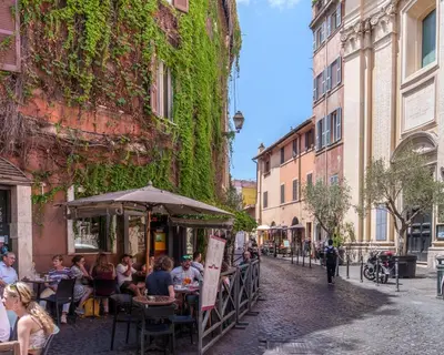 a group of people sitting at an outdoor restaurant on a street at Le Lune Apartment in Rome