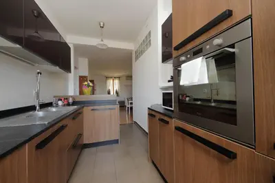 a kitchen with wooden cabinets and a stainless steel appliance at Stazione Trastevere 3BR Flat by Flatinrome in Rome