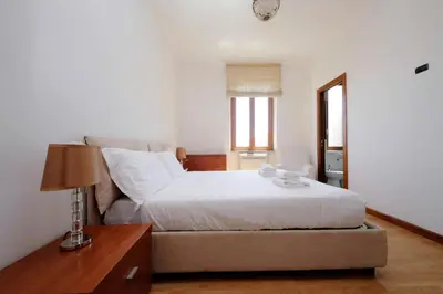 a bedroom with a bed and a table with a lamp at Stazione Trastevere 3BR Flat by Flatinrome in Rome
