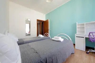 a room with two beds and a desk and a mirror at Stazione Trastevere 3BR Flat by Flatinrome in Rome