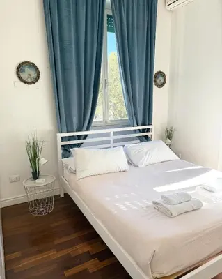 a bedroom with a large bed with blue curtains at Volupta' s house Trastevere Station in Rome