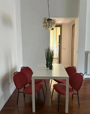 a dining room with a white table and red chairs at Volupta' s house Trastevere Station in Rome