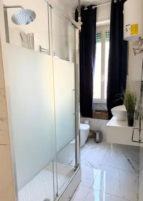 a bathroom with a glass shower with a toilet and a sink at Volupta' s house Trastevere Station in Rome