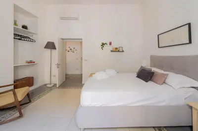 a white bedroom with a large bed and a chair at Falstaff in Rome