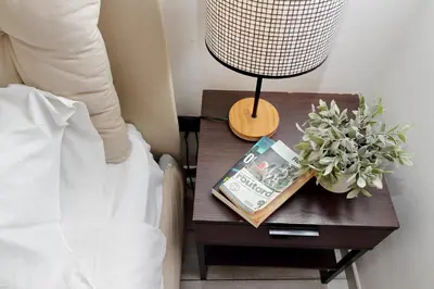 a nightstand with a lamp and a book on a table at Fidelio Holiday Home in Rome