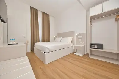 a white bedroom with a bed and a desk at LH Hotel Andreotti in Rome
