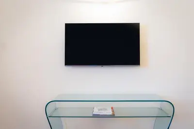 a glass table with a tv on a white wall at Baccina Apartment by Rental in Rome in Rome