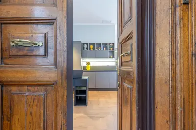 a hallway with a wooden door and a kitchen at Residenza Degli Speziali Roma Prati in Rome