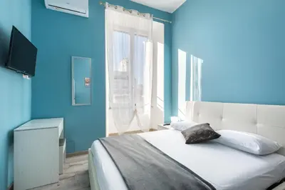 a blue bedroom with a bed and a window at Roma Design Rooms San Giovanni Colosseo Area in Rome