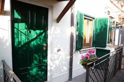 a green door on a house with flowers on a balcony at La casetta nascosta in Rome