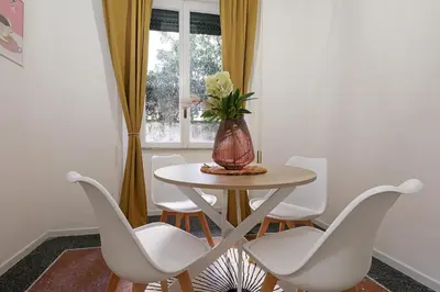 a table with white chairs and a vase with flowers on it at Bologna Garden House in Rome