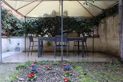 a table and chairs under an umbrella with flowers at Bologna Garden House in Rome