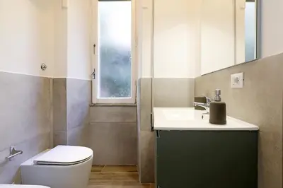 a bathroom with a toilet and a sink and a window at Bologna Garden House in Rome