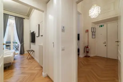 a hallway with white walls and a chandelier at Castro Pretorio 9 - FromHometoRome in Rome