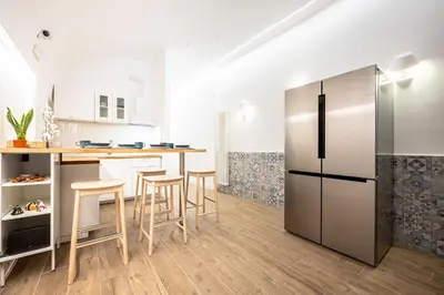 a kitchen with a stainless steel refrigerator and stools at Domus Piramide in Rome