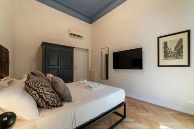 a bedroom with a bed and a tv on the wall at Castro Pretorio 21 - FromHometoRome in Rome