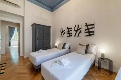 two beds in a room with white walls and wood floors at Castro Pretorio 21 - FromHometoRome in Rome