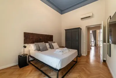 a bedroom with a large bed with a wooden headboard at Castro Pretorio 21 - FromHometoRome in Rome