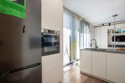 a kitchen with white cabinets and a stainless steel refrigerator at Cottage with Garden and Terrace near Termini in Rome