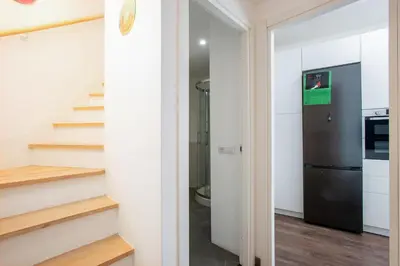 a kitchen with a black refrigerator and stairs at Cottage with Garden and Terrace near Termini in Rome