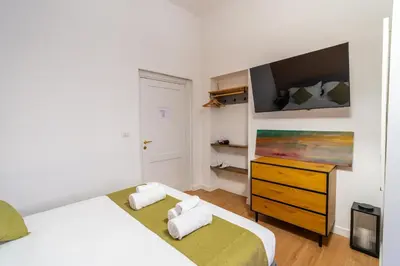 a bedroom with two beds and a dresser with a tv at NOI Luxury rooms Colosseum in Rome