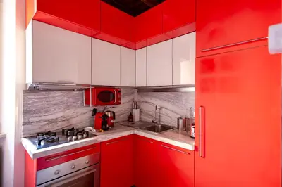 a red and white kitchen with a sink and a stove at Elegantis Josephine Suite - Elegance near Spanish Steps Trevi and Pantheon in Rome