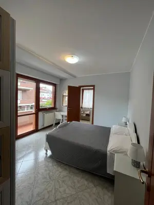 a bedroom with a bed and a large window at Trilocale con terrazza e garage in Rome