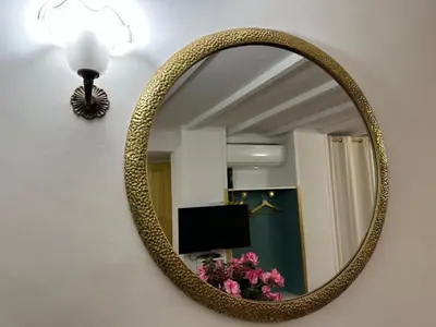 a mirror on a wall with a lamp and flowers at incanto e campo de fiori in Rome