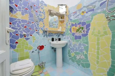 a bathroom with a sink and a toilet with a mosaic wall at Casa Gaudì in Rome