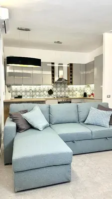 a blue couch in a living room with a kitchen at AliHouse Apartment in Rome
