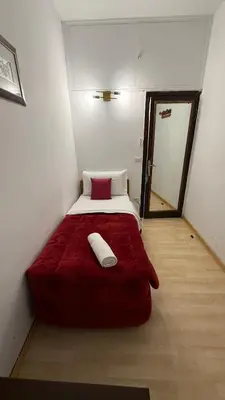 a small bedroom with a bed with a red blanket at Two Ducks Hostel in Rome