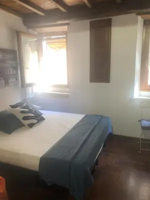 a large bed in a room with two windows at Trastevere Mini-apartment in Rome