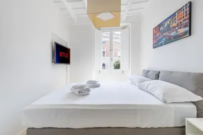 a large white bed in a white room with a window at Maison Parlamento - Roma centro in Rome