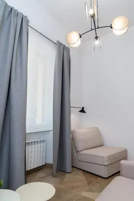 a living room with gray curtains and a chair at Angelico living Rome in Rome