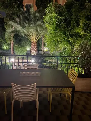 a table and chairs with a palm tree in the background at Dolcevita suite in Rome
