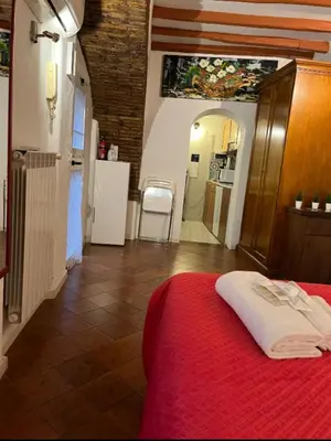 a bedroom with a red bed and a kitchen at Arco acetari-Il medio evo nel cuore di roma in Rome