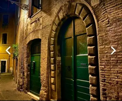 two green doors on the side of a brick building at Arco acetari-Il medio evo nel cuore di roma in Rome