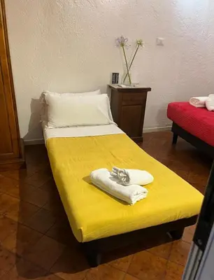 a room with a yellow bed with towels on it at Arco acetari-Il medio evo nel cuore di roma in Rome