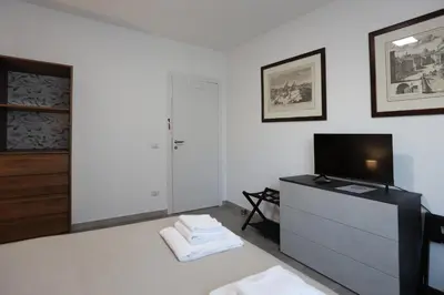 a white living room with a tv and a dresser at Sweet Home Fleming in Rome