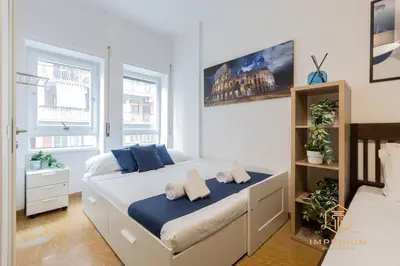 a white bedroom with a large bed with blue pillows at Imperium Garbatella Guesthouse - 2 bedrooms with private bathroom, Terrace, 800mt to metro in Rome